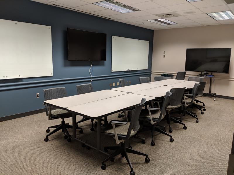 6 movable tables with about 10 wheeled chairs, 2 large monitors, and two whiteboard on wall